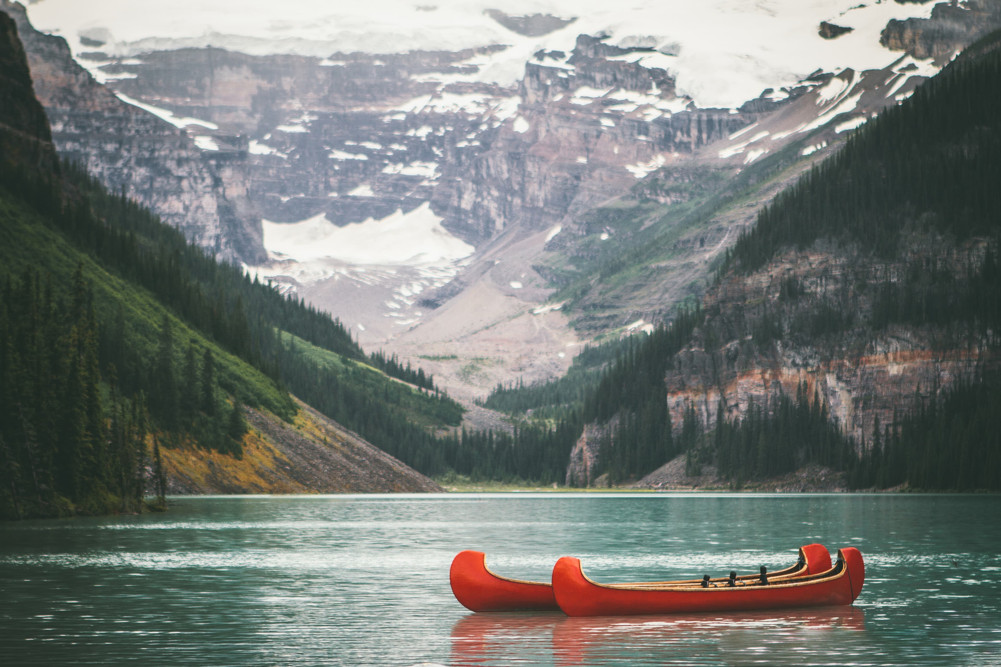 two red canoes in the lake with mountains in the background